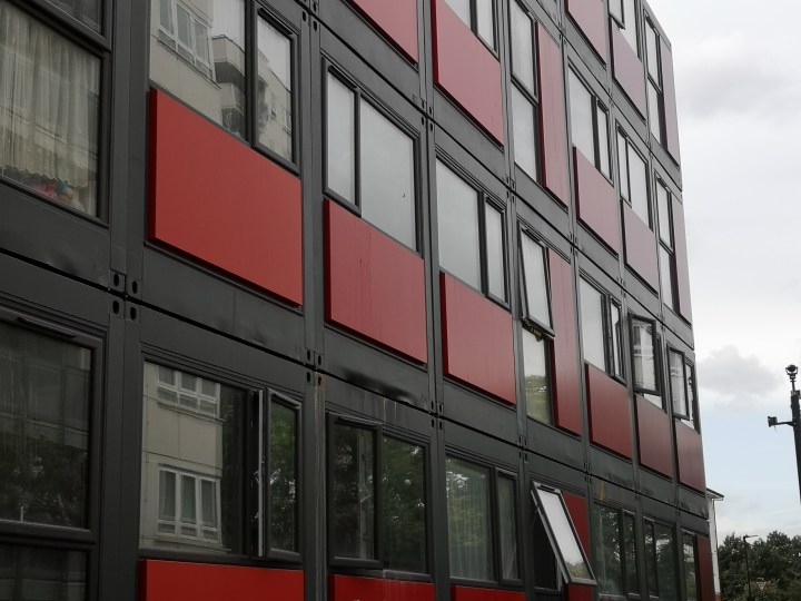 One of the facades of Hope Gardens, with its windows reflecting the adjacent high-rise tower blocks